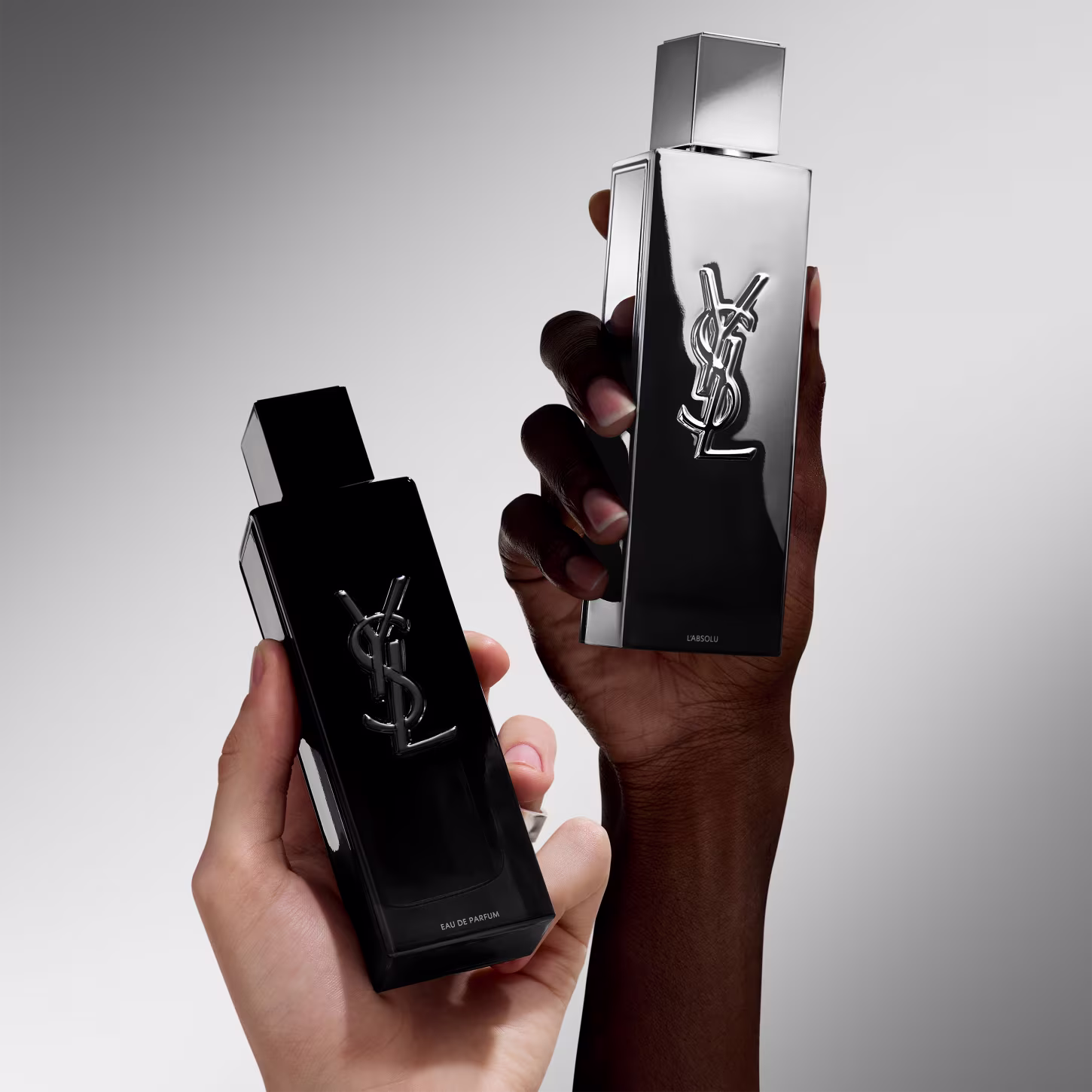 Frasco de perfume de design minimalista prateado, com o logotipo da marca Yves Saint Laurent em destaque. A embalagem possui uma forma geométrica simples e elegante, com uma tampa destacada no topo.