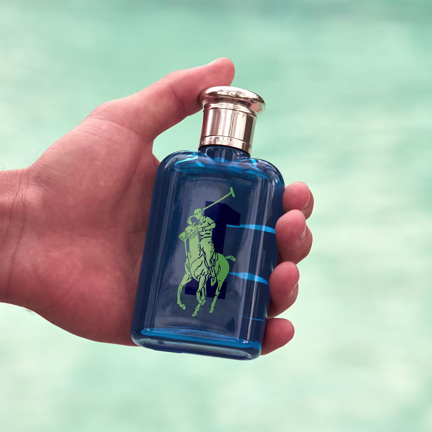 Frasco de perfume Big Pony 1 azul com logotipo verde da marca Ralph Lauren em destaque. Embalagem de vidro com tampa prateada, apresentando design elegante e minimalista.
