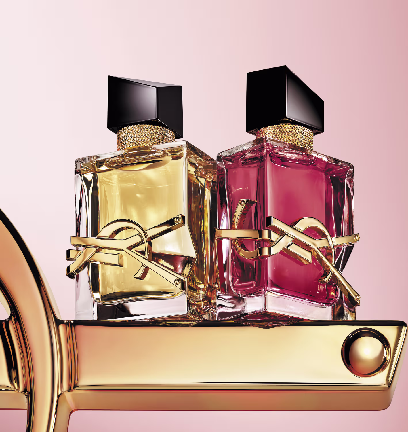 Frasco de perfume vermelho com detalhes dourados, tampa preta e decoração em formato de laço dourado. O rótulo exibe o nome da marca em letras douradas.