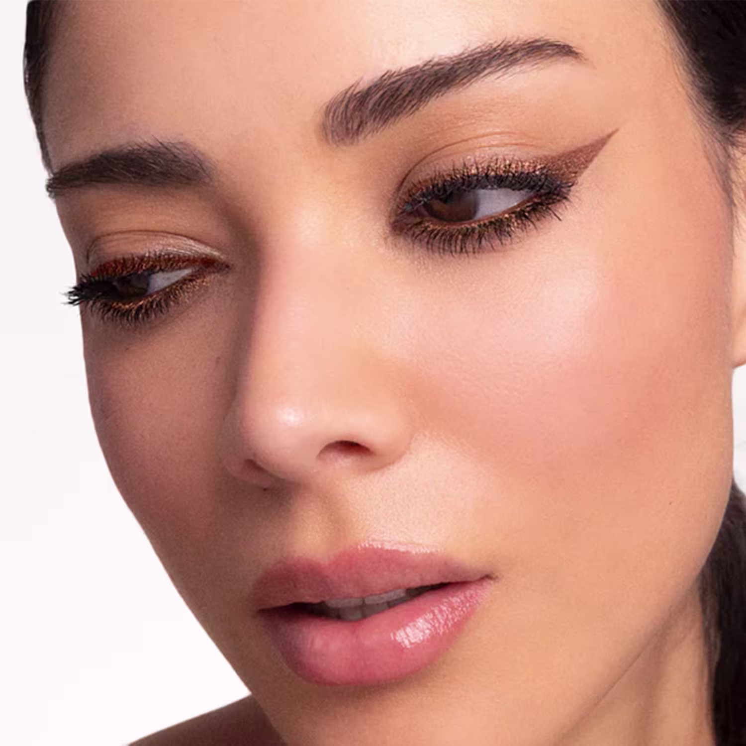 Imagem de close-up de rosto feminino com maquiagem sofisticada, evidenciando olhos e sobrancelhas bem delineados, em um ambiente de estúdio fotográfico com iluminação suave e neutra.