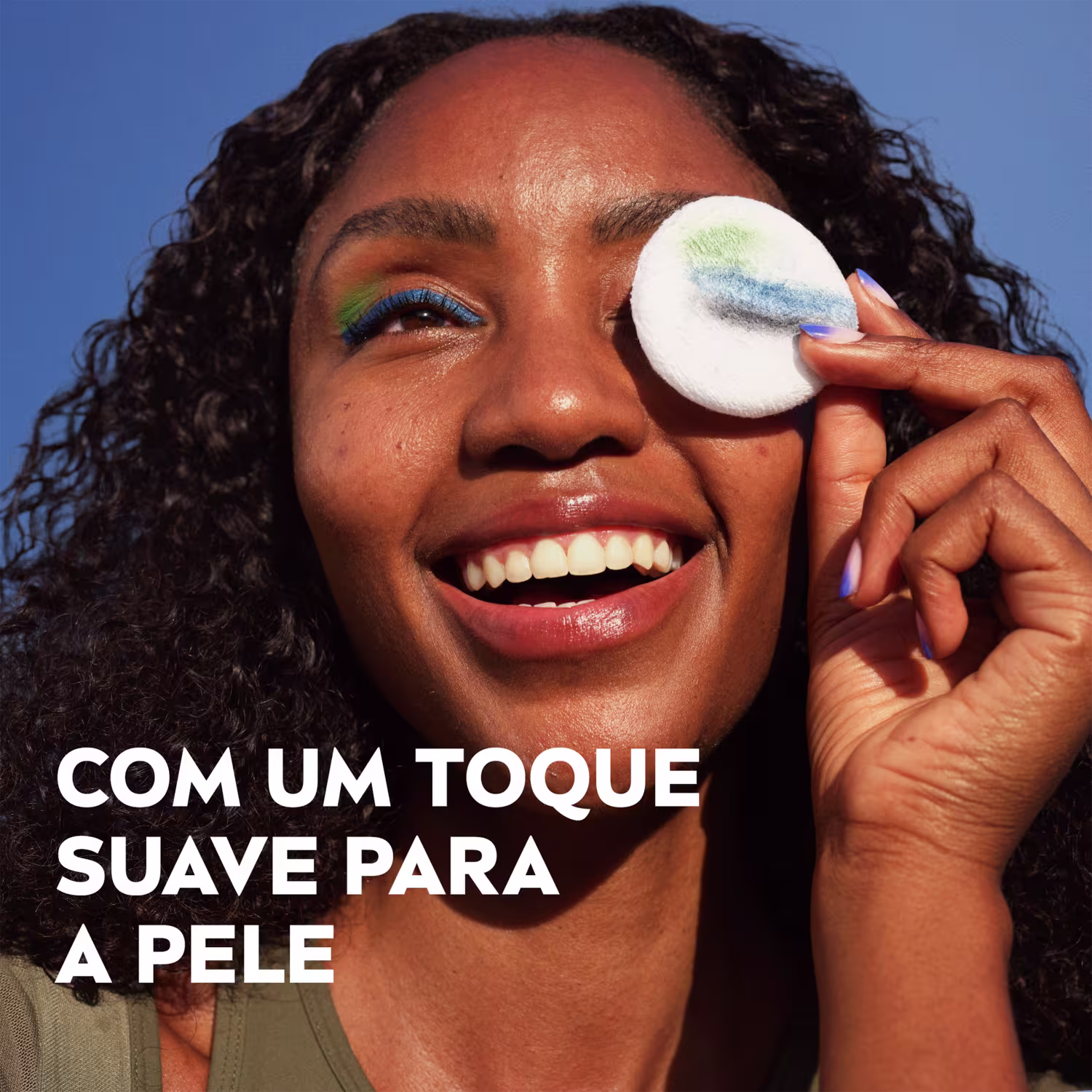 Mulher sorridente segurando um aplicador de maquiagem branco com texto "Com um toque suave para a pele" em português.