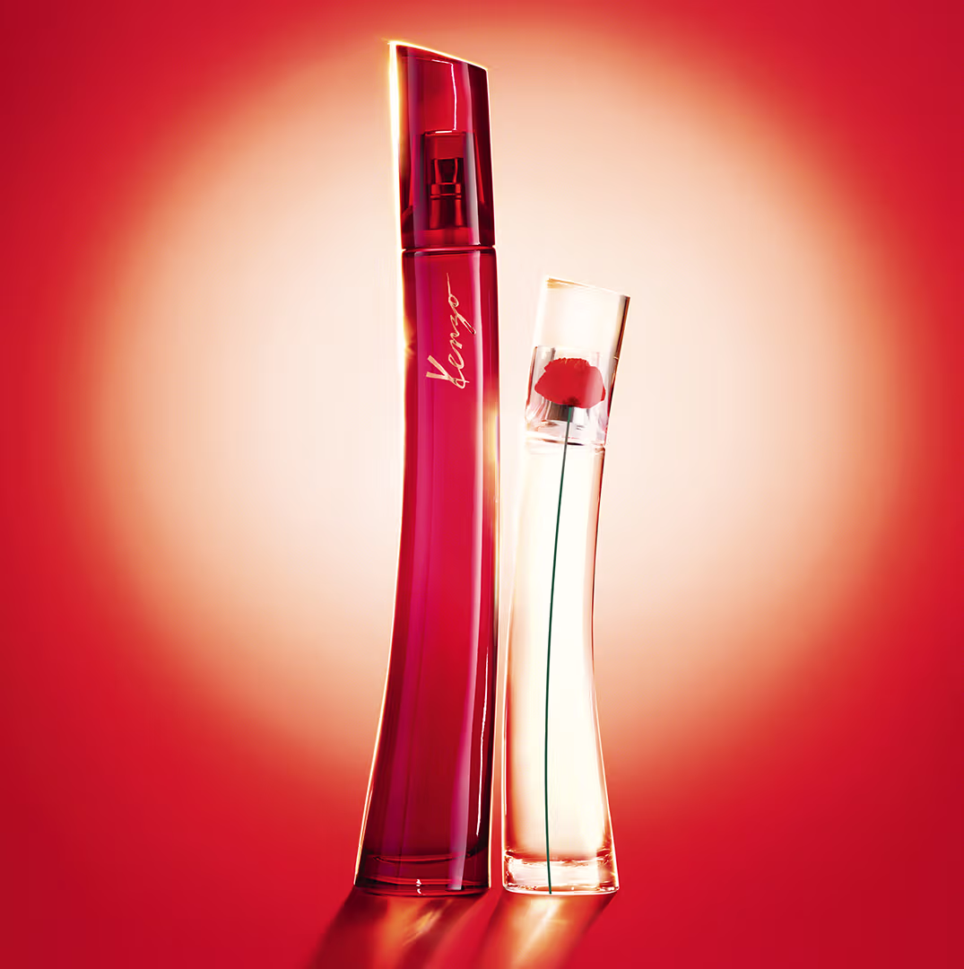 Dois itens de perfumaria em fundo vermelho-alaranjado. Um frasco vermelho com rótulo  e outro frasco transparente com líquido transparente. Ambos os frascos têm formas elegantes e design moderno.