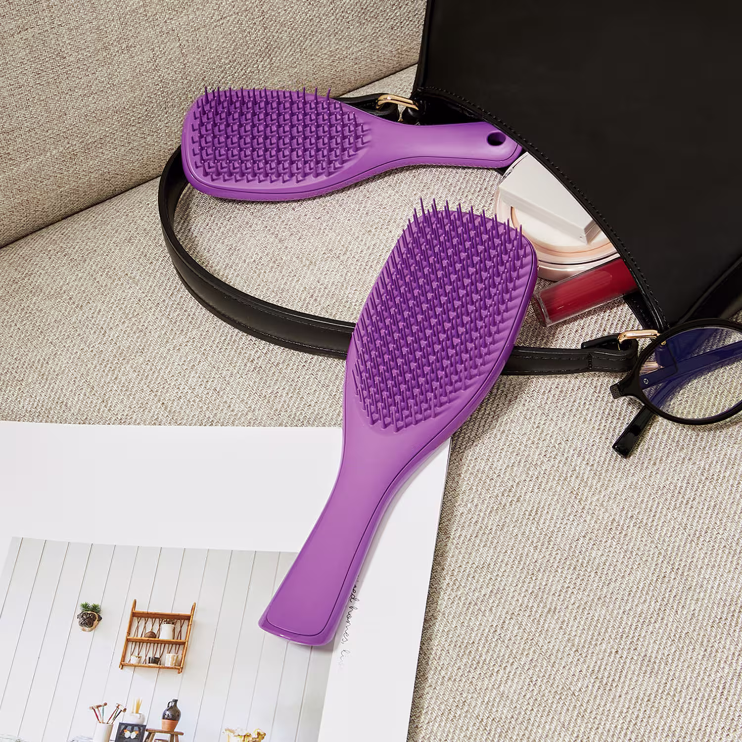 Ambiente de uso de produto de beleza da marca, com escova de cabelo e acessórios de maquiagem em uma bolsa preta sobre um fundo bege texturizado.