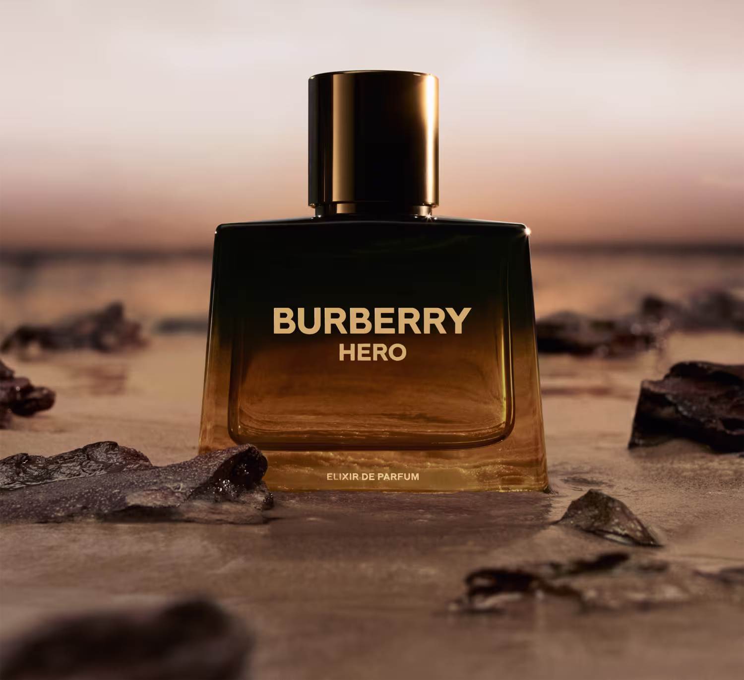 Frasco  preto e dourado em gradiente com rótulo em letras douradas exibindo o texto "BURBERRY HERO".