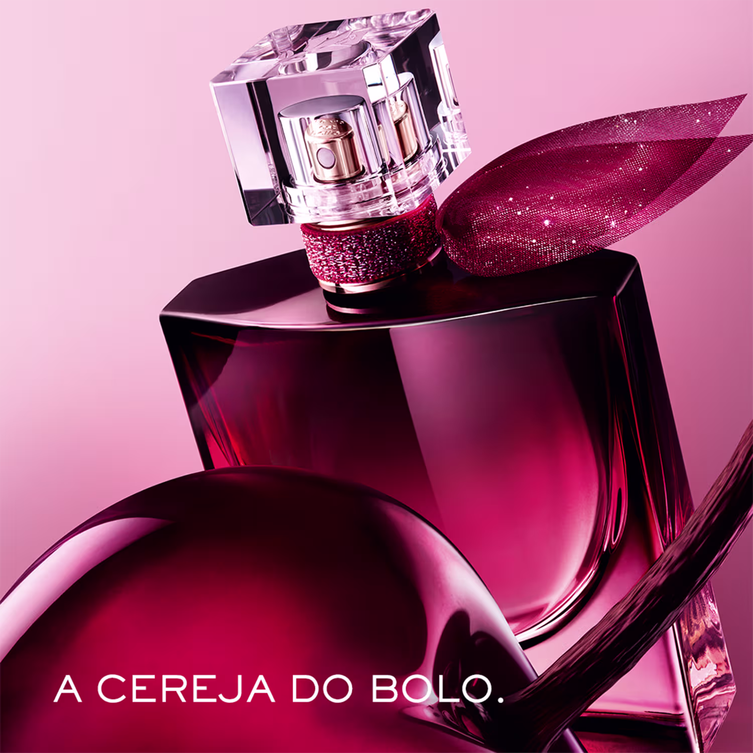 Frasco de perfume Lancôme com tampa de cristal, embalado em caixa vermelha com texto "A CEREJA DO BOLO". Predominância de tons de vermelho e rosa, com detalhes brilhantes e textura aveludada.