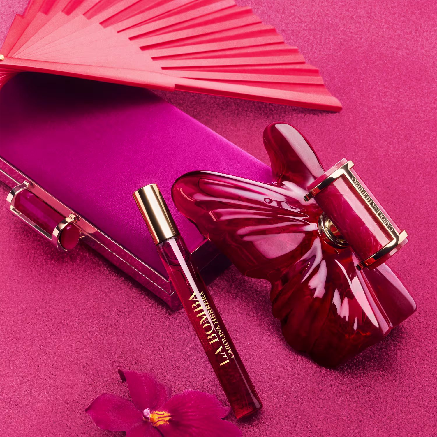 Conjunto de produtos de beleza da marca Carolina Herrera, incluindo um frasco de perfume com tampa dourada e um travel size, todos com embalagens em tons de rosa intenso e detalhes dourados.