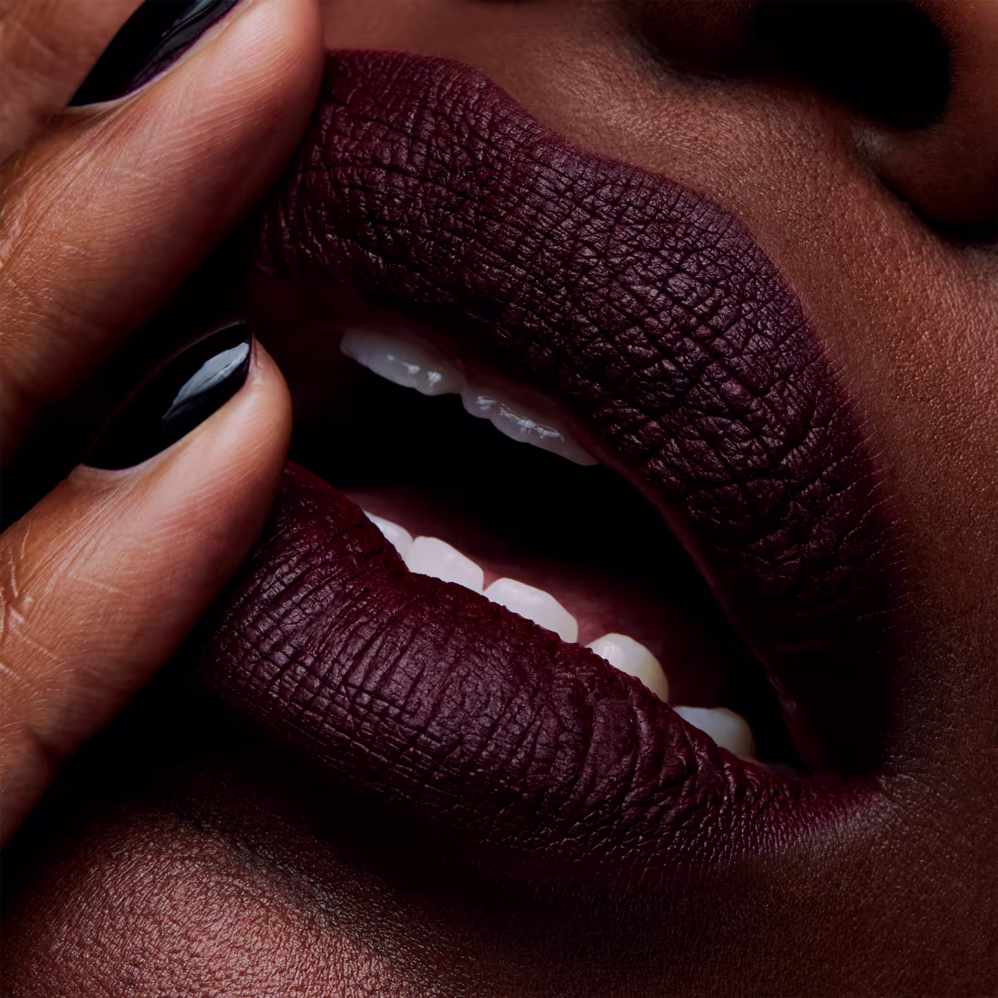 A imagem mostra um close nos lábios maquiados, revelando a cobertura intensa e pigmentada do produto. A embalagem ou rótulo não estão visíveis, apenas o resultado final da aplicação do batom, que confere um visual sofisticado e impactante.