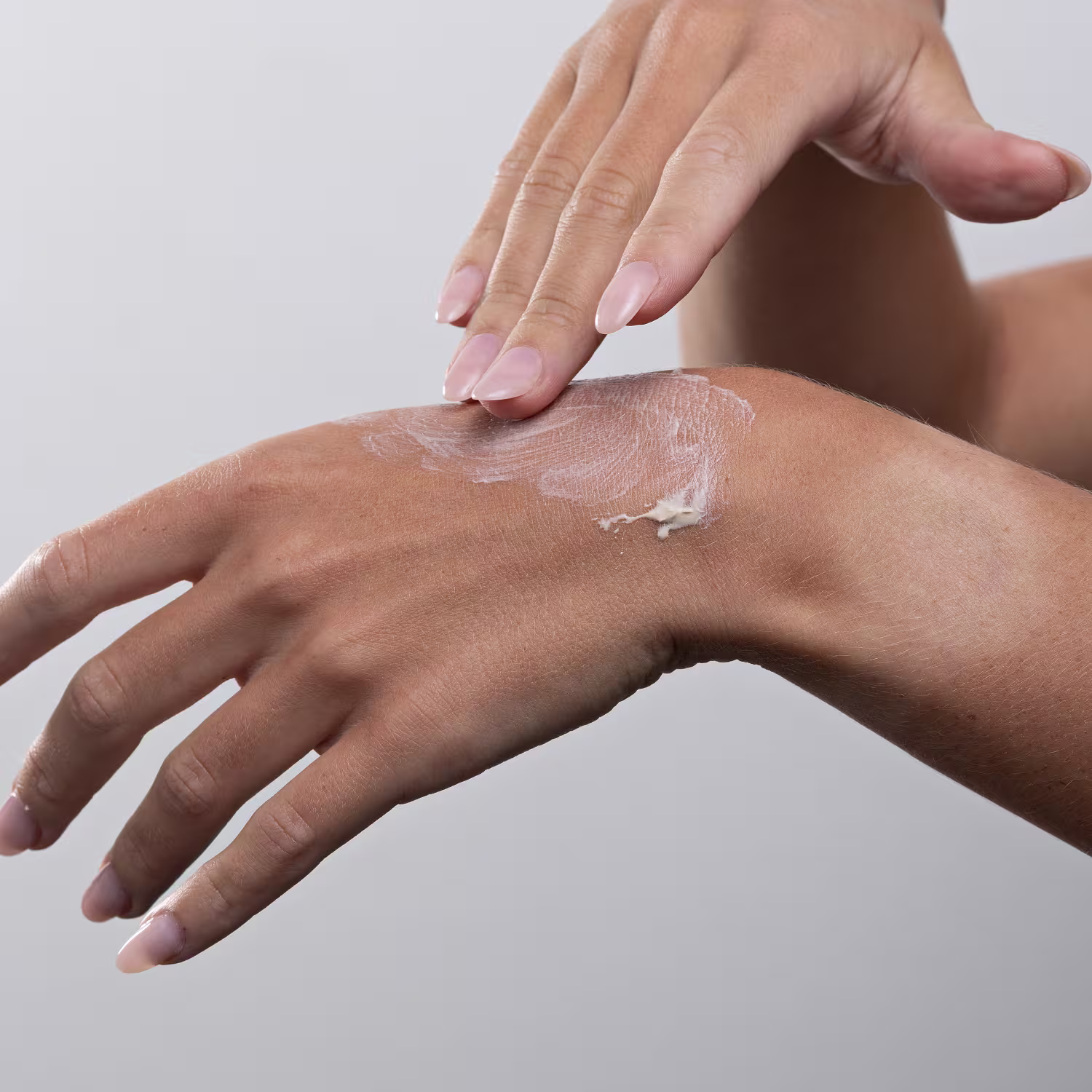 Mãos femininas aplicando o produto.