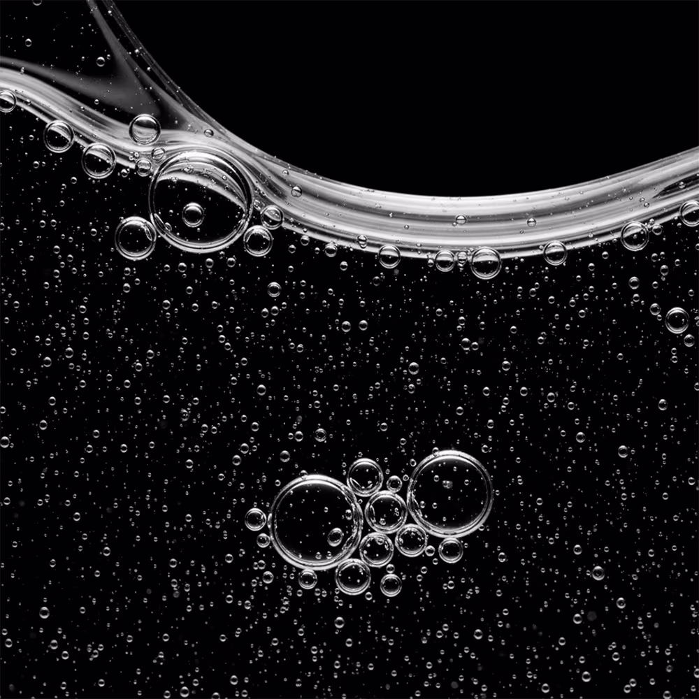 A imagem mostra uma textura de bolhas e gotas de água transparentes em um fundo escuro. A textura é fluida, brilhante e com uma aparência líquida, com diferentes tamanhos de bolhas e gotas dispersas uniformemente.