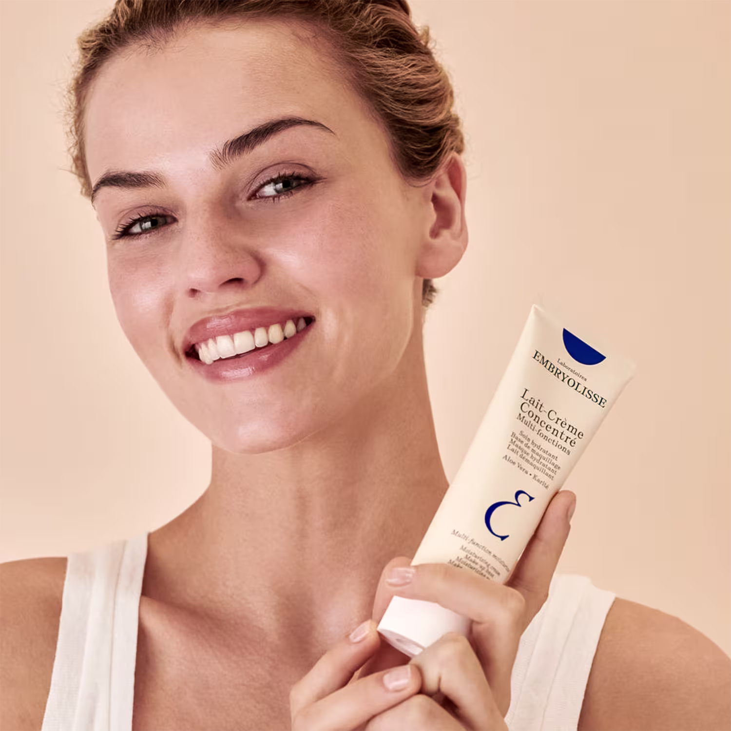A imagem mostra uma mulher sorridente segurando a embalagem ao lado do rosto.