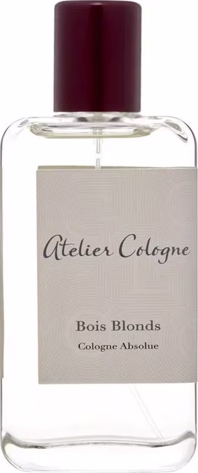 Perfume em frasco de vidro transparente retangular com tampa de plástico marrom escuro. Rótulo bege com o texto "Atelier Cologne" e "Bois Blonds Cologne Absolue" impresso em letras escuras.