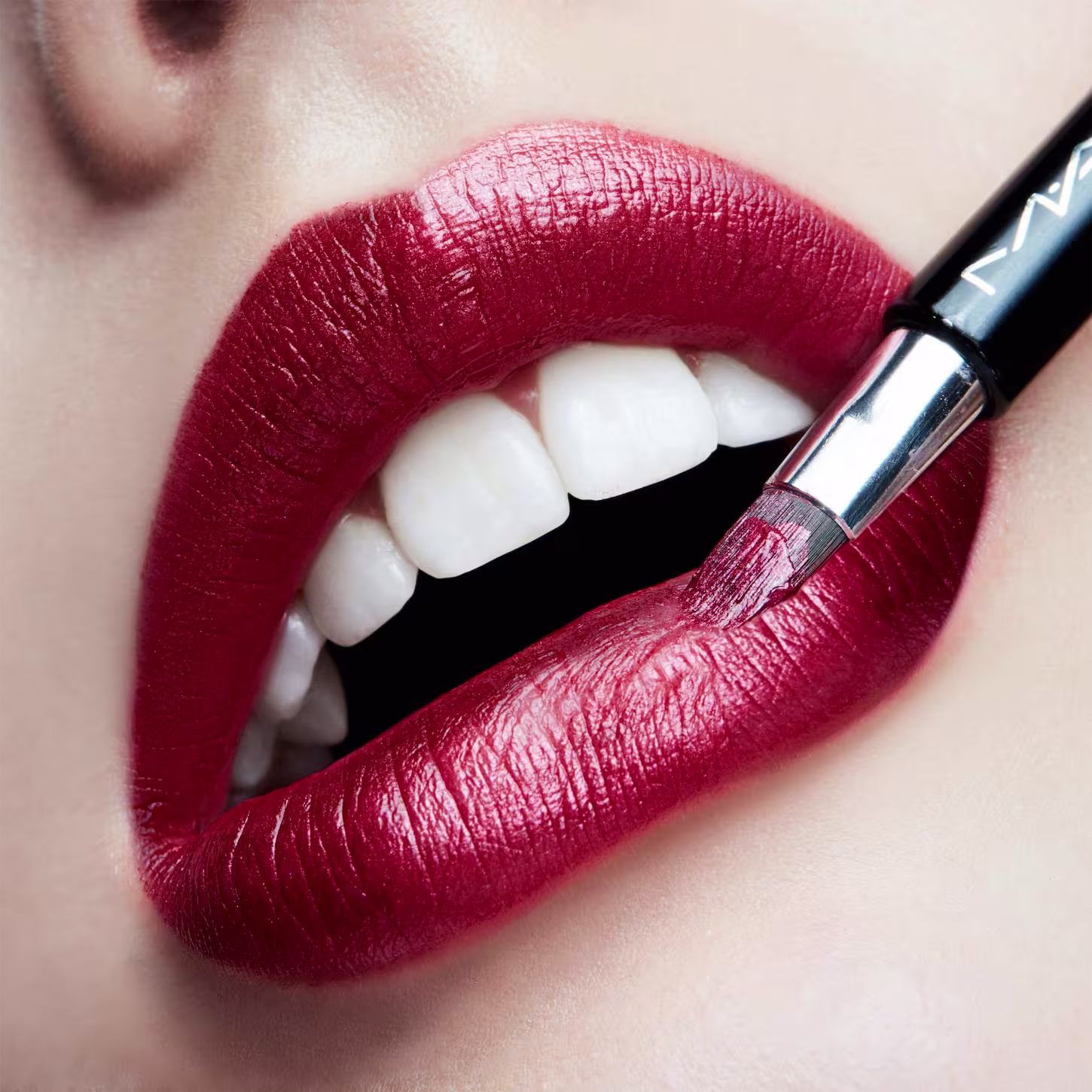 A imagem mostra a boca de uma mulher usando o batom.