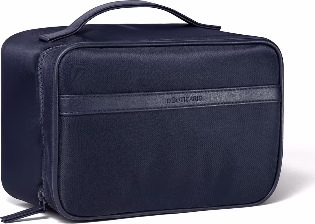 Ela possui um design simples e elegante, com uma alça superior para transporte. A bolsa é feita de material resistente e possui um zíper central para acesso ao interior. O logotipo da marca Boticário está visível na parte frontal da bolsa.