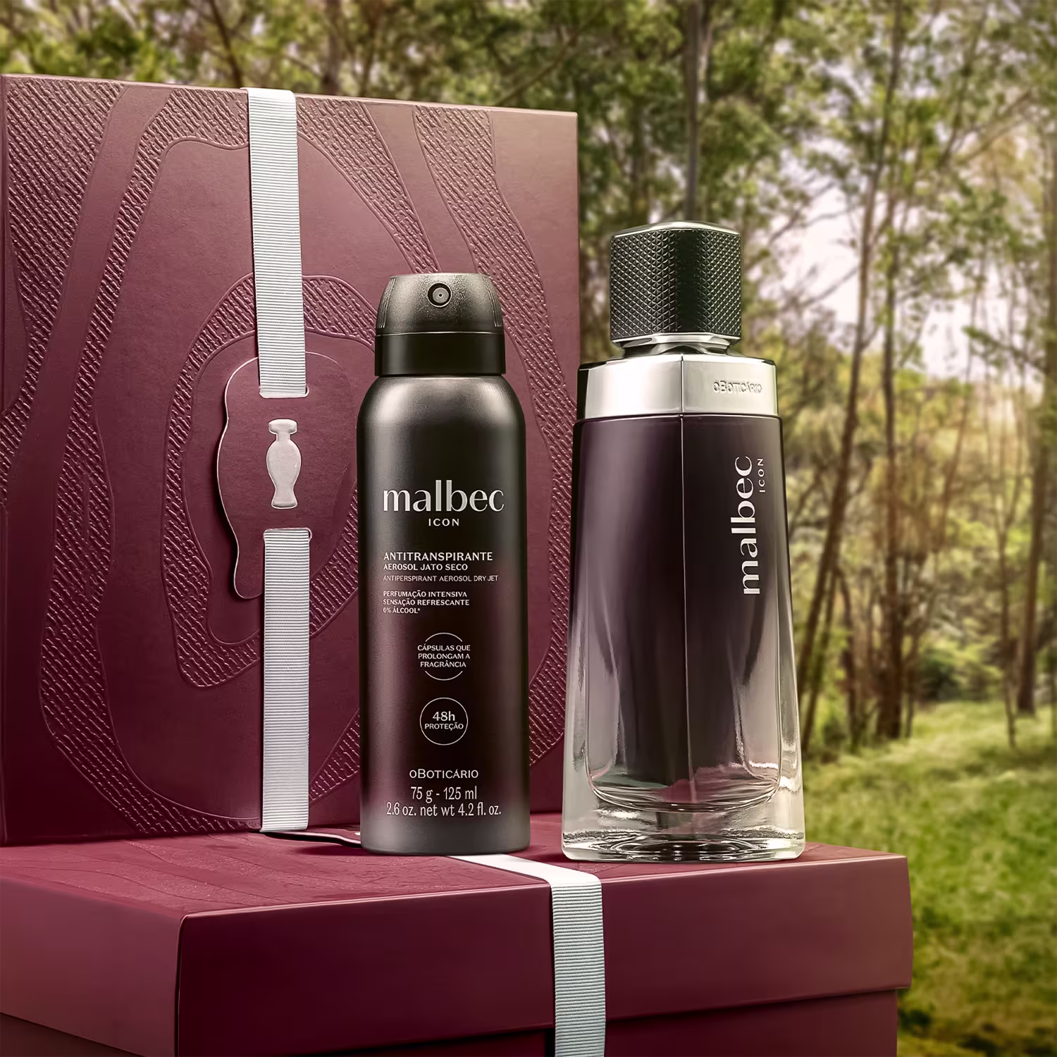 Caixa e embalagem de item de perfumaria da marca Malbec em primeiro plano, com floresta verde ao fundo, em uma superfície de madeira.