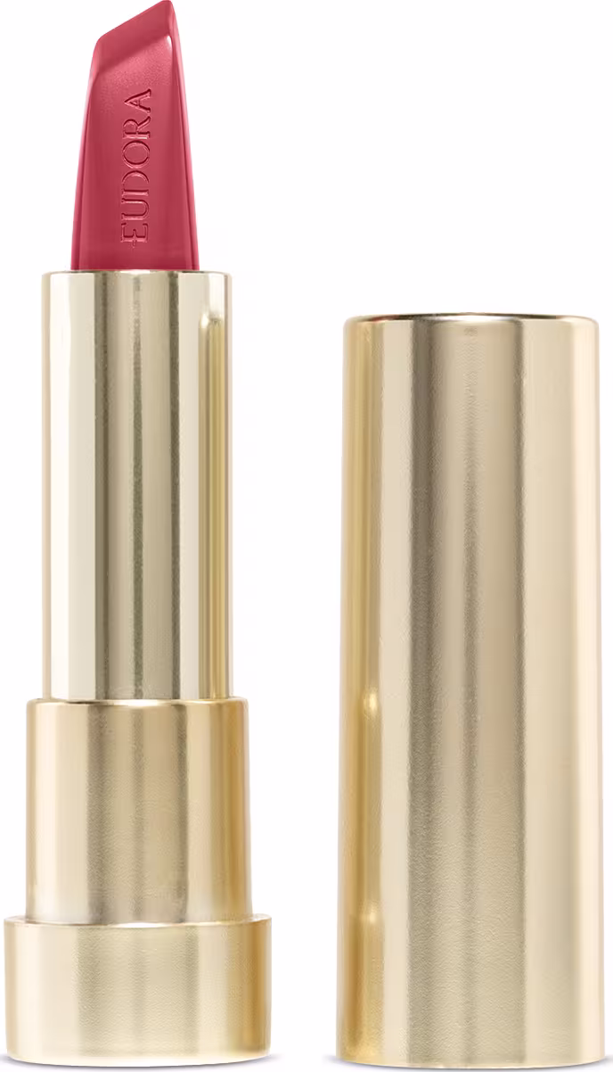 Na imagem o Batom Eudora Glam Amulips na cor Alaranjado Destemido, um tom de alaranjado terroso. O batom está aberto, revelando seu interior com o nome Eudora gravado no produto. A embalagem dourada transmite a elegância e qualidade do produto.