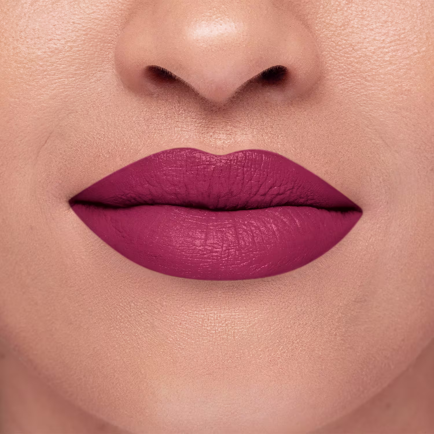 A imagem mostra um close do batom aplicado nos lábios de uma pessoa branca. Os lábios parecem macios e bem delineados, com um acabamento discretamente brilhante. O tom rosa transmite uma aparência sofisticada e elegante.