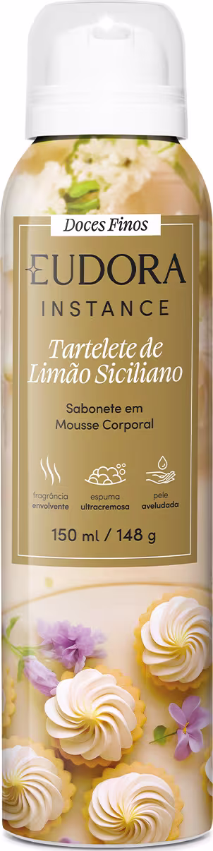 Embalagem em frasco plástico com tampa branca. Rótulo mostra merengues decorativos e flores lilás, no cento, um retângulo dourado com o nome Eudora Instance e detalhes do produto.150ml/148g. Propriedades hidratante, antioxidante e pele aveludada.