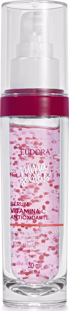 A imagem mostra um frasco pequeno, cilíndrico, transparente com tampa também transparente, visto de frente. O rótulo tem fundo rosa claro com detalhes em vermelho, exibindo o nome do produto, marca e volumetria com letras rosa e branca,