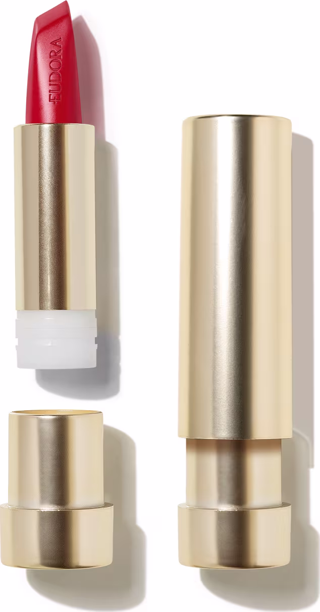 Na imagem o Batom Eudora Glam Amulips. O batom está aberto, revelando seu interior com o nome Eudora gravado no produto. A embalagem dourada transmite a elegância e qualidade do produto.
