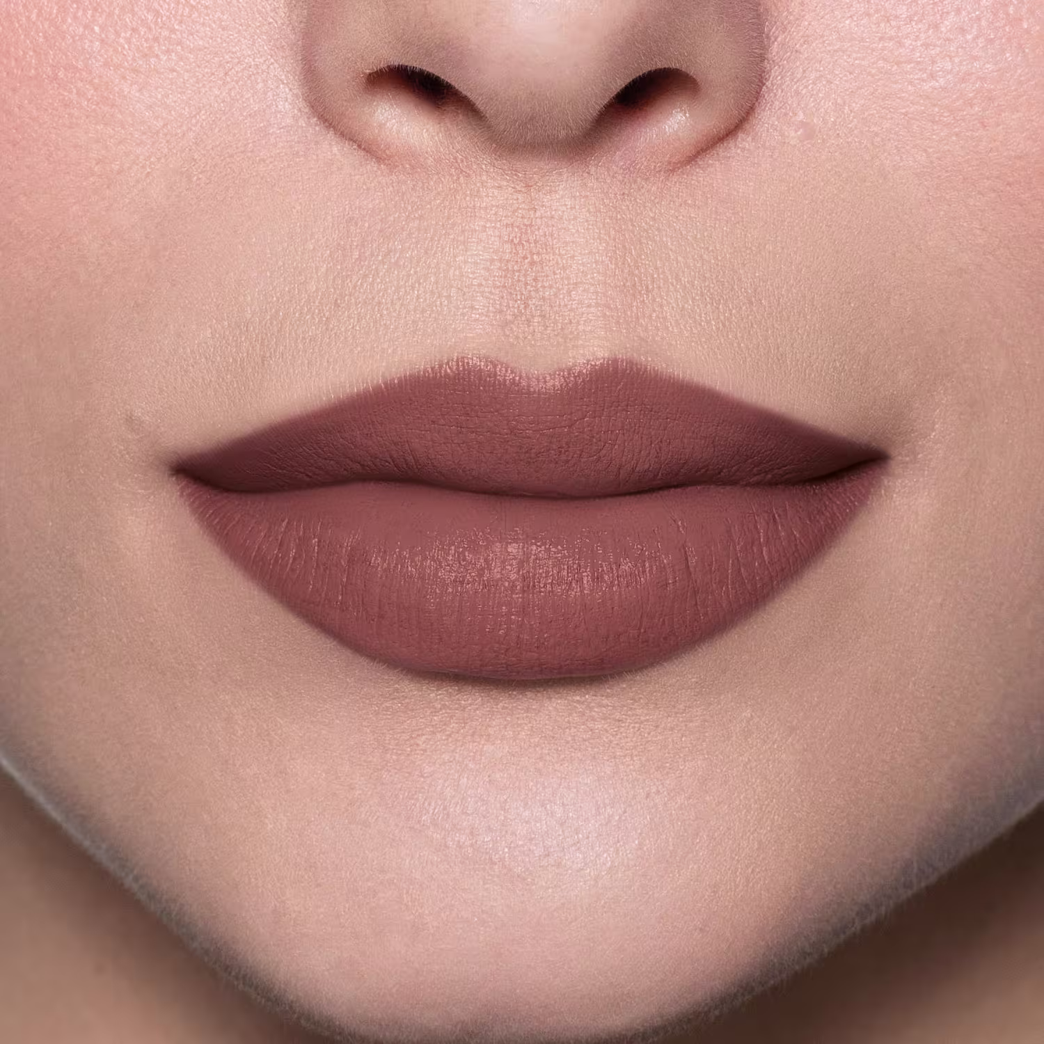 Esta imagem mostra um close-up de lábios femininos com o batom mate marrom determinado, de uma cor achocolatada intensa e vívida. Os lábios têm uma aparência aveludada e bem preenchida, ressaltando a textura sedosa do produto.