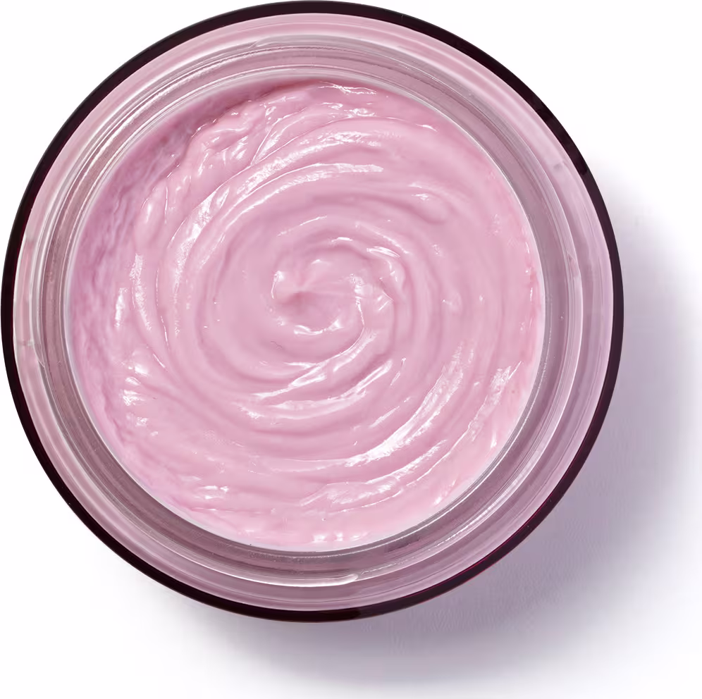 A imagem mostra um creme hidratante de cor rosa claro em um pequeno pote ou recipiente redondo de plástico transparente. O produto tem uma textura cremosa e aveludada, com uma espiral bem definida em seu centro devido à sua consistência densa.