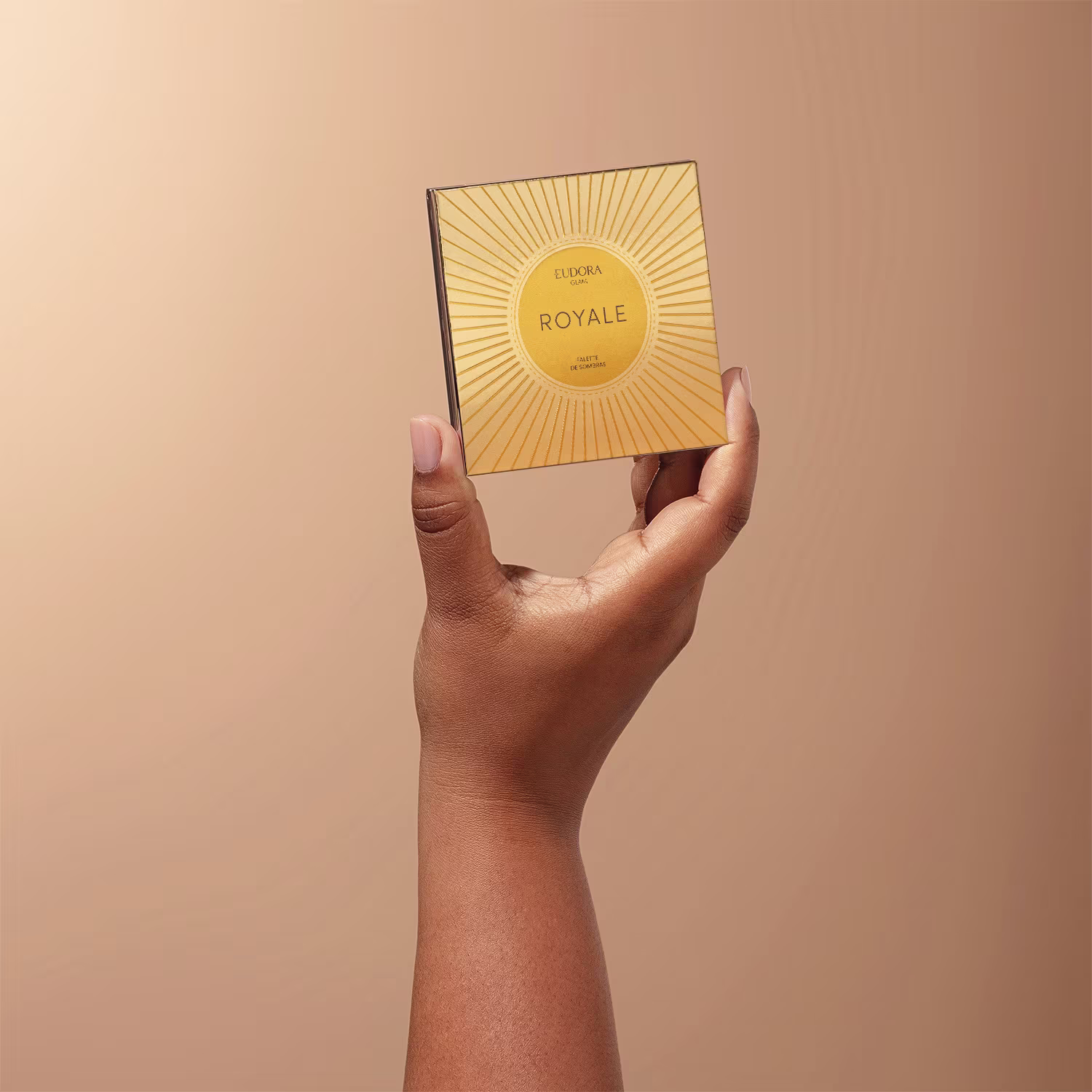A imagem mostra uma mão feminina segurando a Paleta Eudora Glam Royale