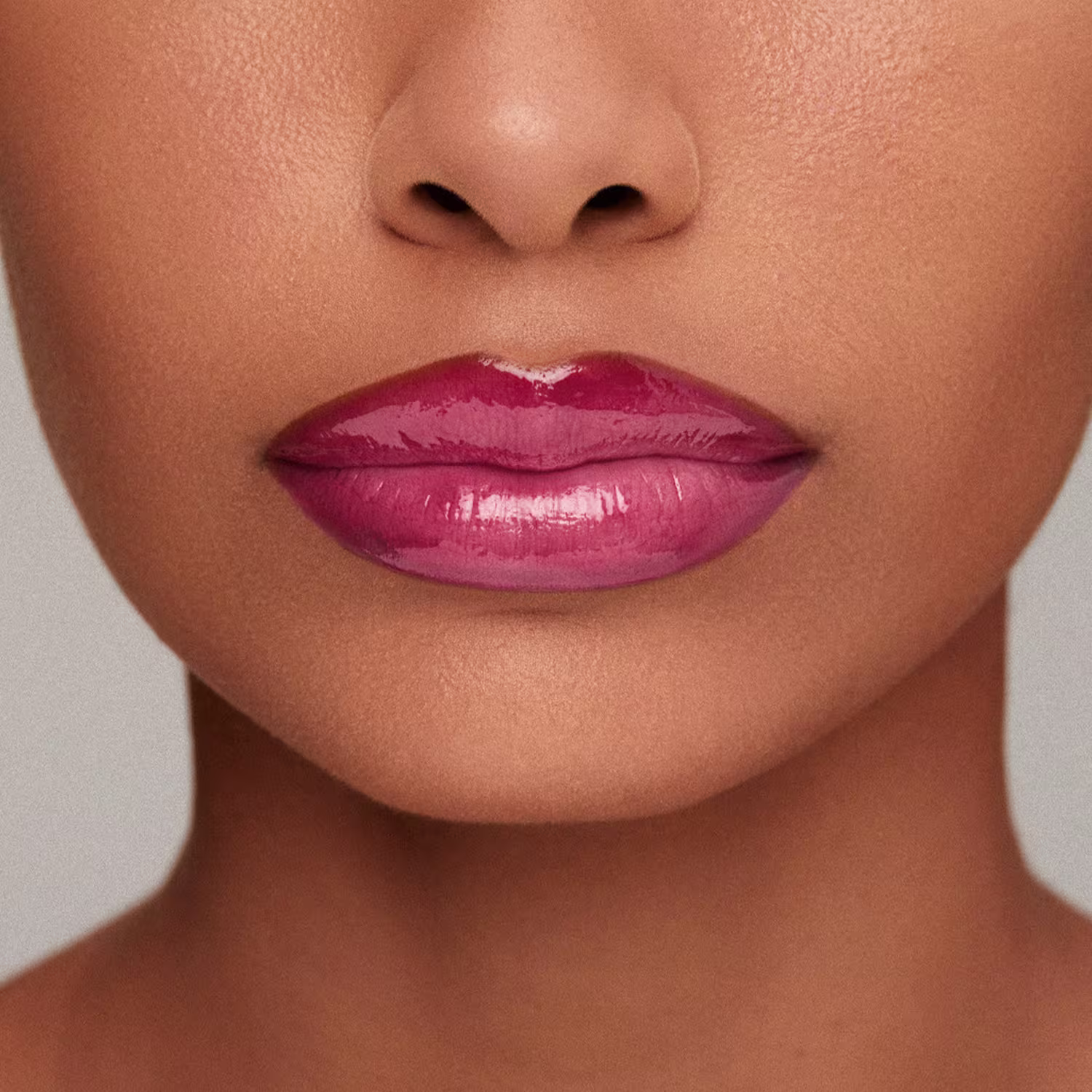 Imagem em close-up dos lábios de uma modelo, mostrando o efeito do Gloss: Lábios levemente avermelhados com brilho, em primeiro plano, sobre fundo neutro.
