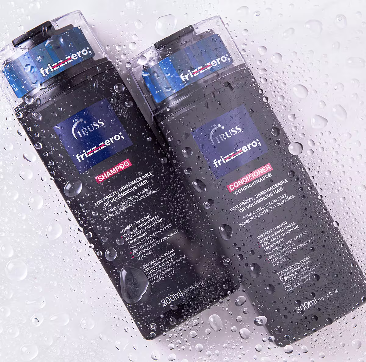 A imagem mostra duas embalagens da marca Truss, de produtos chamados "Shampoo Frizz-Zero" e "Condicionador Frizz-Zero". As embalagens estão molhadas, dando a impressão de que estão submersas ou acabaram de sair da água.