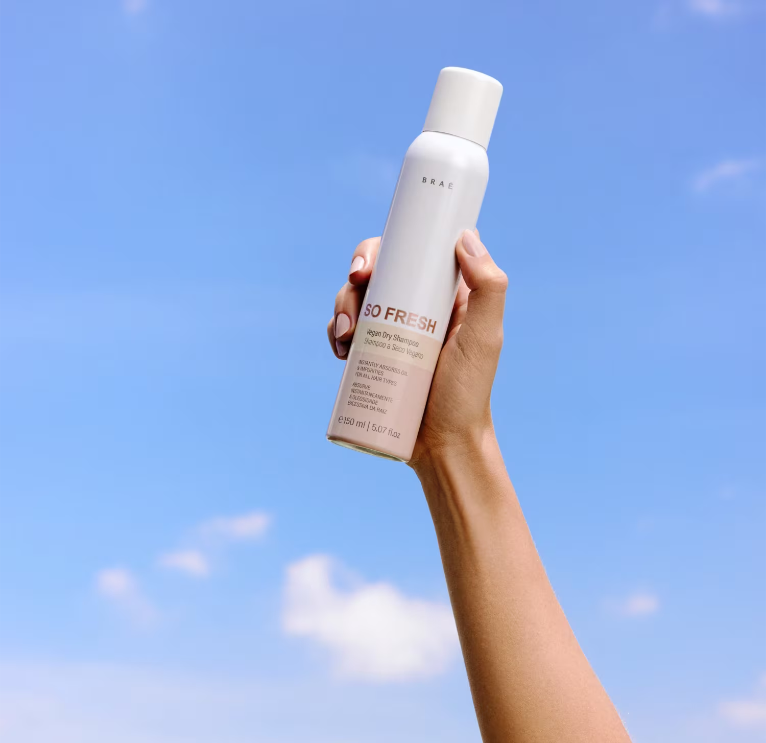 Produto de cuidados capilares da marca Braé. Frasco cilíndrico branco fosco com tampa da mesma cor. Rótulo com o nome do produto "So Fresh Vegan Dry Shampoo" e descrição "Refresca e dá volume".