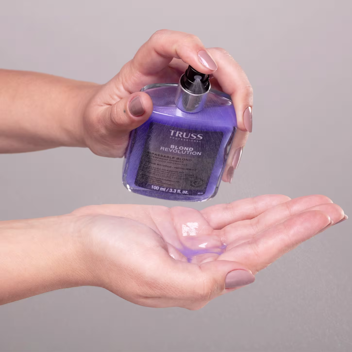 Imagem mostra uma mão borrifando uma amostra do produto, que tem a cor roxa.