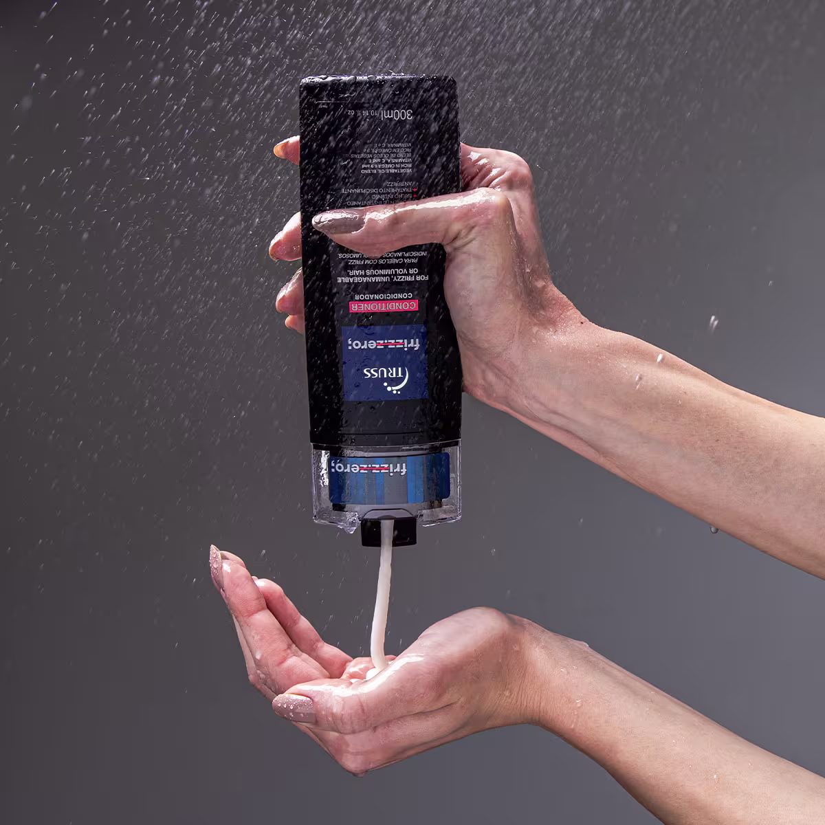 Condicionador da marca Truss. Frasco plástico preto retangular com rótulos azuis e vermelhos. O líquido está sendo despejado do frasco em uma mão aberta, com gotas caindo.