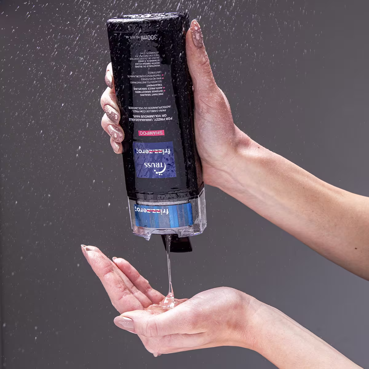 Shampoo da marca Truss. Frasco plástico preto retangular com rótulos azuis e vermelhos. O líquido está sendo despejado do frasco em uma mão aberta, com gotas caindo.