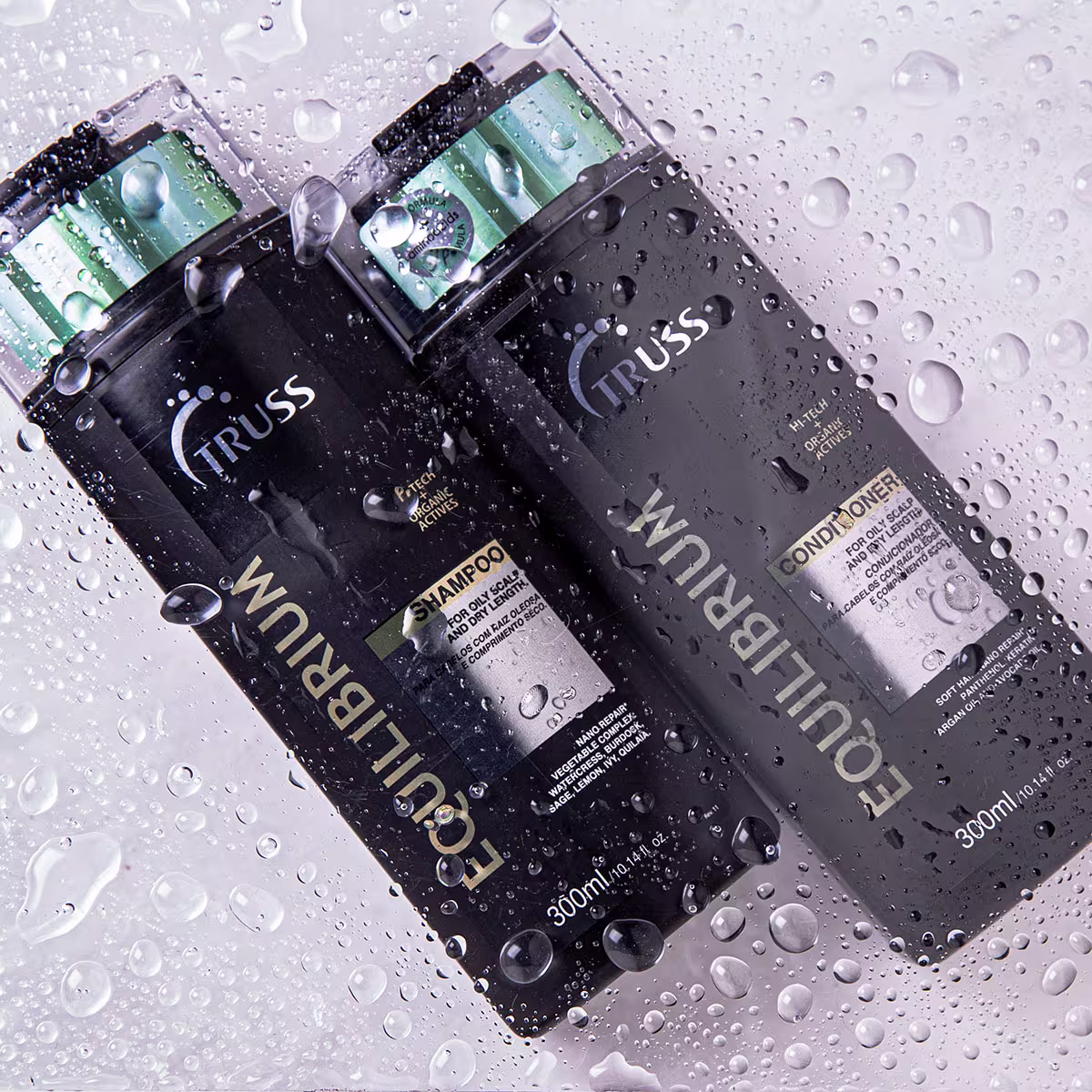 Shampoo e condicionador Equilibrium. Embalagens plásticas pretas. Informações como ingredientes e volume de 300ml impressas nas embalagens. Gotas de água condensadas cobrindo as superfícies, criando um efeito molhado.