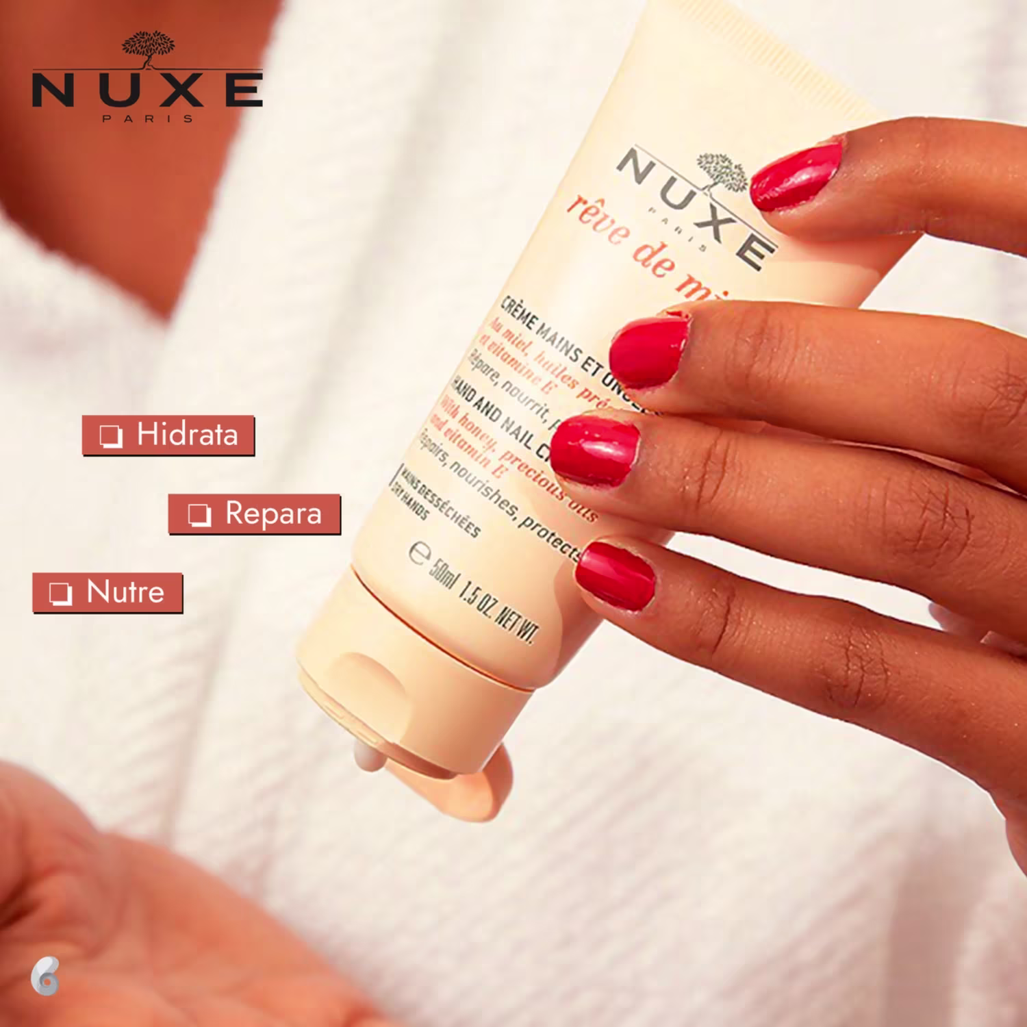 Uma mão feminina segura o creme Nuxe, enquanto aplica o produto na outra mão.