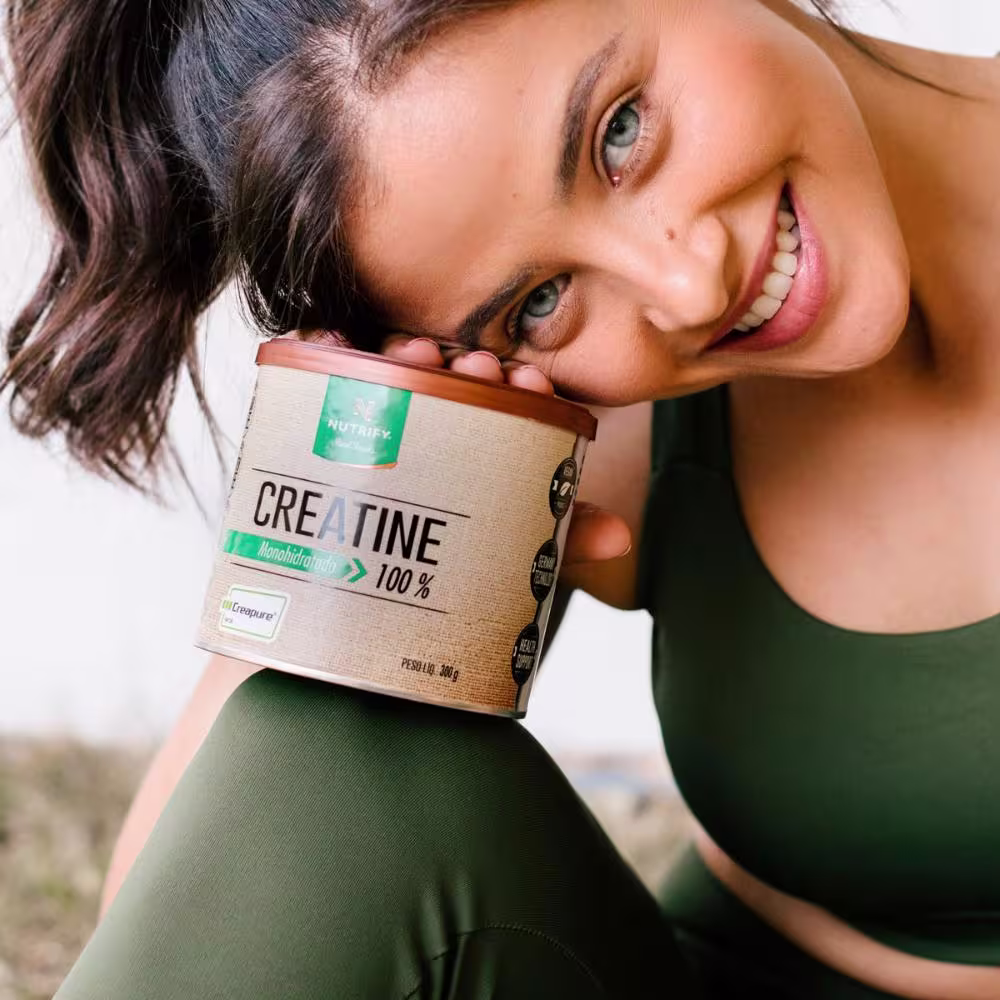 Modelo segurando a lata do Suplemento Alimentar em Pó Nutrify Creatine Monohidratada 100% 300g.