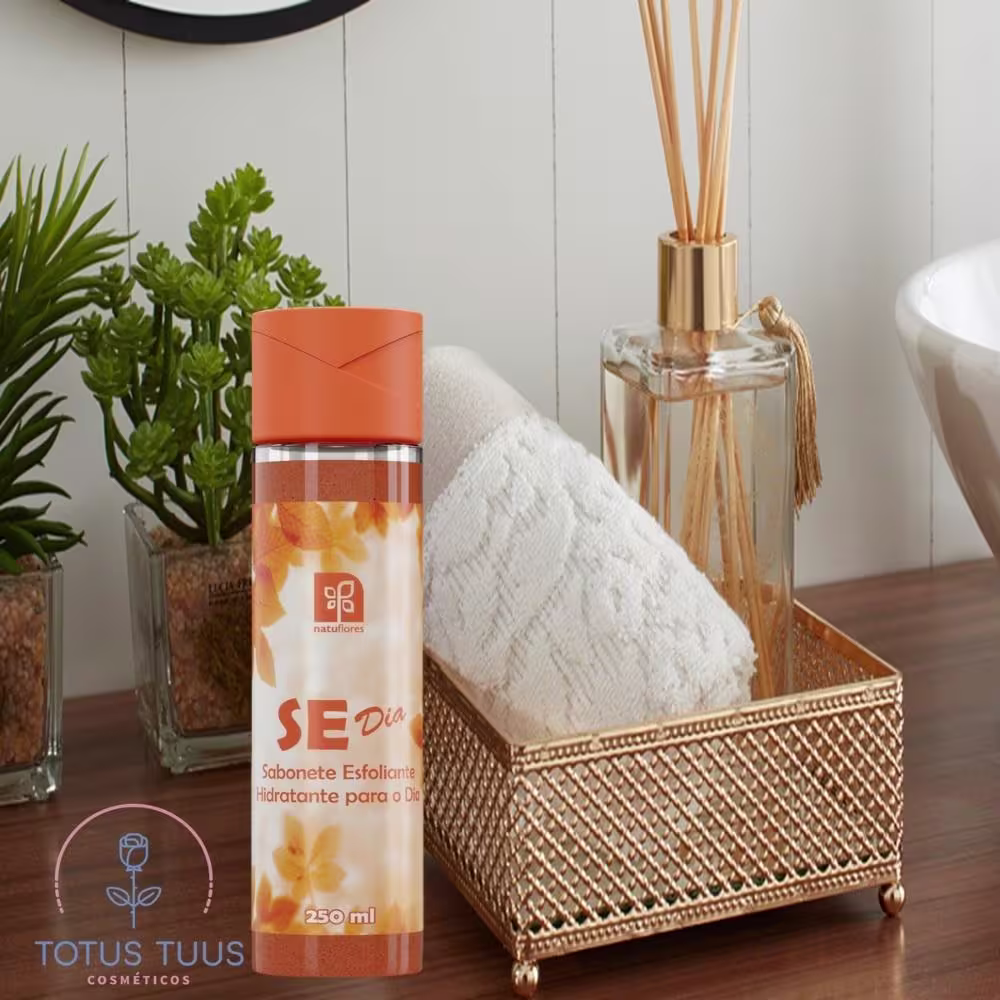 Sabonete esfoliante hidratante para o dia da marca Natuflores. Embalagem em frasco cilíndrico transparente de 250ml com tampa laranja. Rótulo laranja com detalhes em branco e amarelo, exibindo o nome do produto "SE Dia".