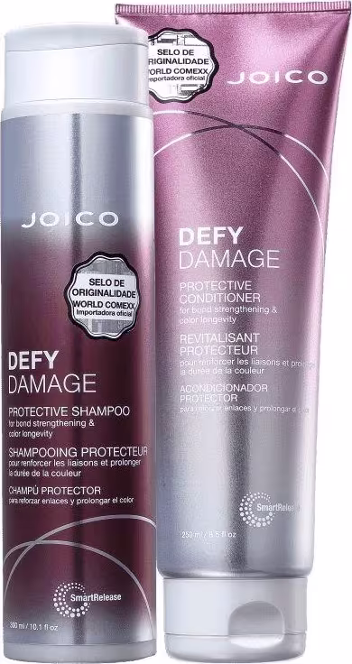 A imagem mostra dois produtos da linha "Defy Damage" da marca Joico: shampoo e condicionador. As embalagens são roxas com tons prateados e letras brancas.