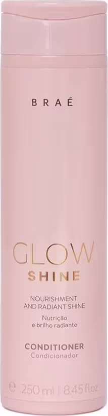 Condicionador Glow Shine da marca Brae. Embalagem cilíndrica rosa claro em plástico. Rótulo na frente com o nome do produto "Glow Shine" e a descrição "Nourishment and Radiant Shine" (Nutrição e Brilho Radiante) em letras douradas.