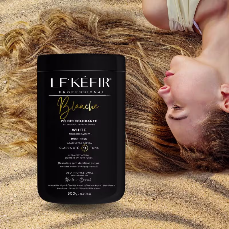 A imagem mostra o pote do pó descolorante posicionado junto a longos cabelos loiros espalhados, pertencentes a uma pessoa que não é totalmente visível na foto.
