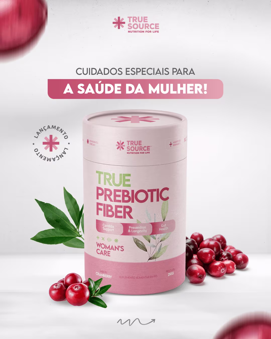 Produto de cuidados femininos True Prebiotic Fiber da marca True Source. Imagem mostra o produto acompanhado de folhas verdes e cranberries. Cores predominantes são rosa, verde e vermelho. Texto em português "Cuidados Especiais para a Saúde da Mulher!"