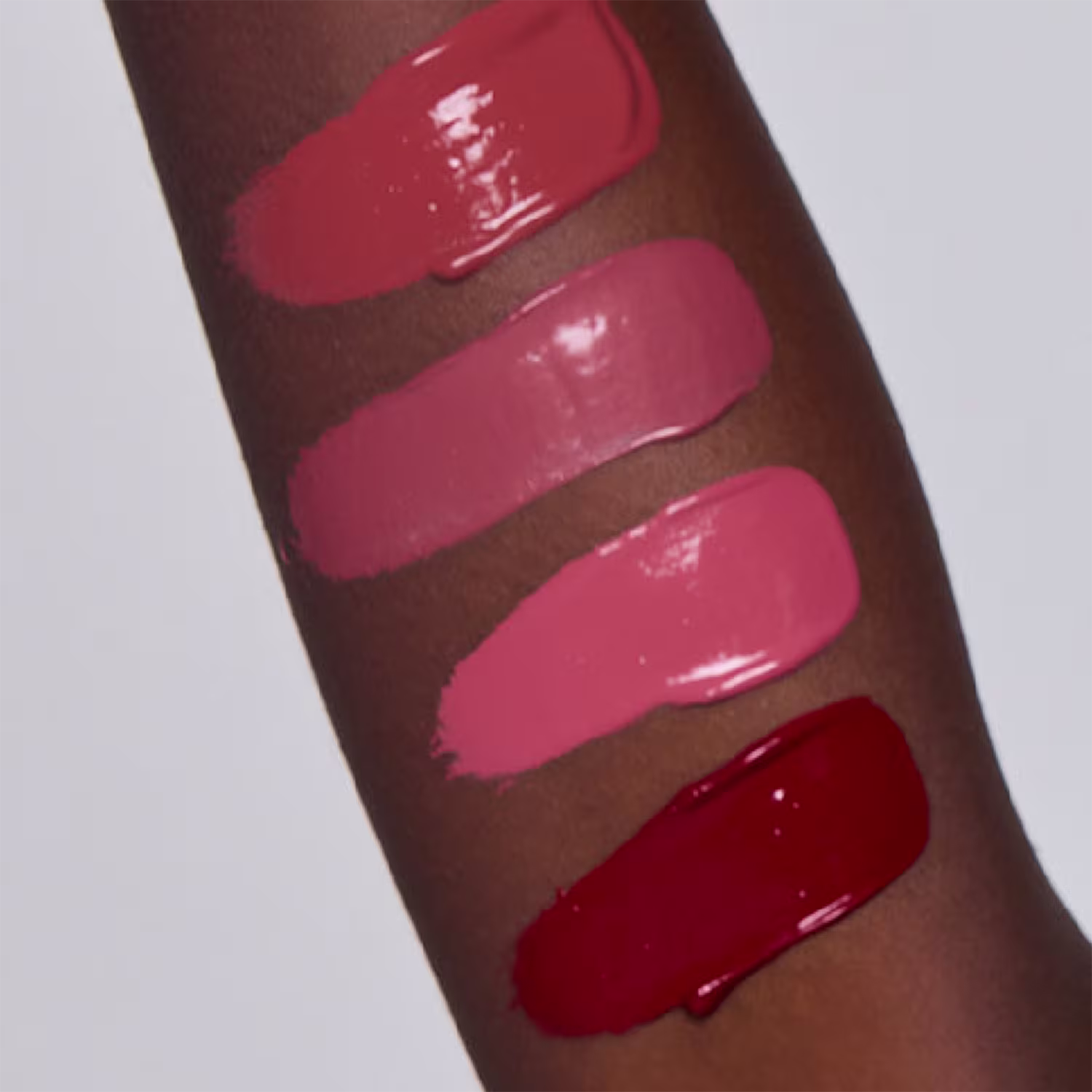 A imagem mostra amostras de diferentes tonalidades do batons com uma paleta de cores avermelhadas e rosadas. Parecem ser produtos de maquiagem para realçar e colorir os lábios em tons que vão desde um rosa claríssimo até um vermelho intenso e chamativo.