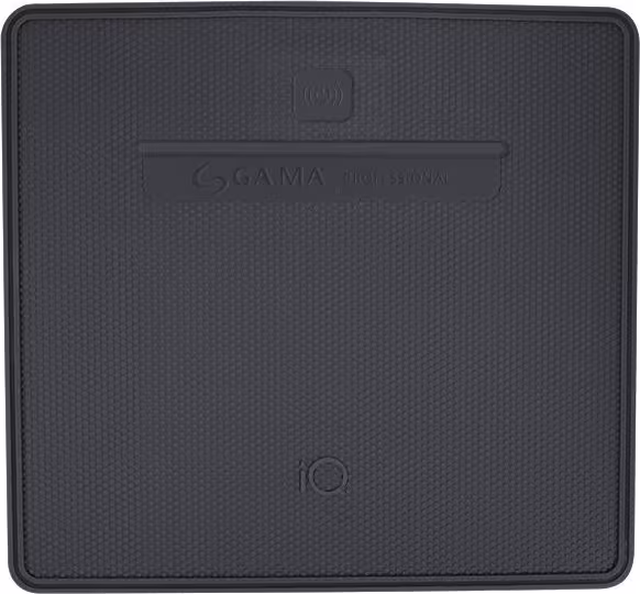 A imagem mostra o carregador sem fio/smart pad cinza escuro da marca GA.MA Italy. O dispositivo tem uma superfície texturizada e formato quadrado.