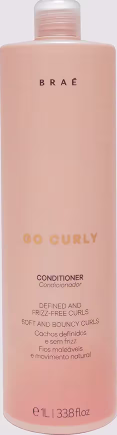 Frasco de condicionador Brae Go Curly, com embalagem rosa clara e rótulo com texto em amarelo e branco, indicando que o produto é para cachos definidos e sem frizz.
