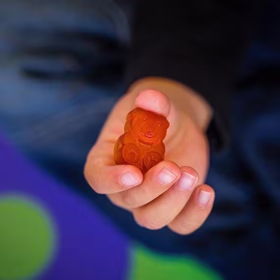 A imagem mostra uma mão segurando uma gominha vermelha.