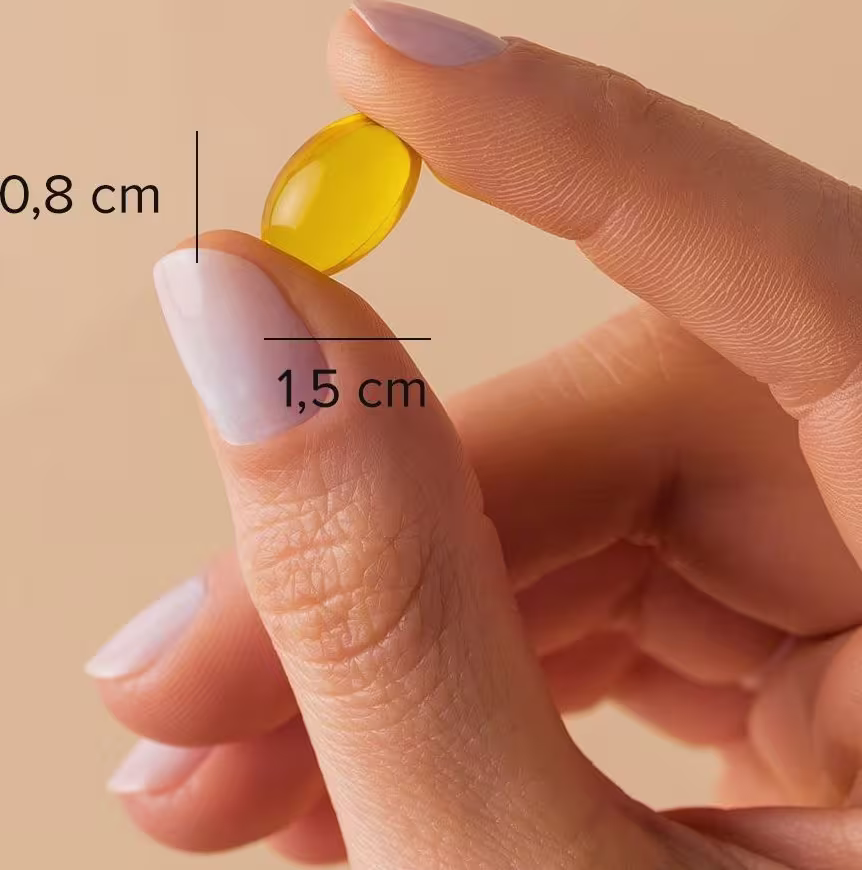 A imagem mostra uma mão segurando uma cápsula com o dedo polegar e o indicador. Além de indicar o tamanho da cápsula: 0,8cm x 1,5cm.