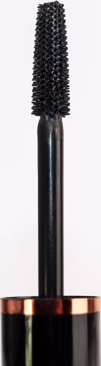 Rímel em formato de tubo preto com detalhes em cobre na base. O aplicador possui cerdas densas e compridas na cor preta. O produto é da marca Ustē Cosméticos.