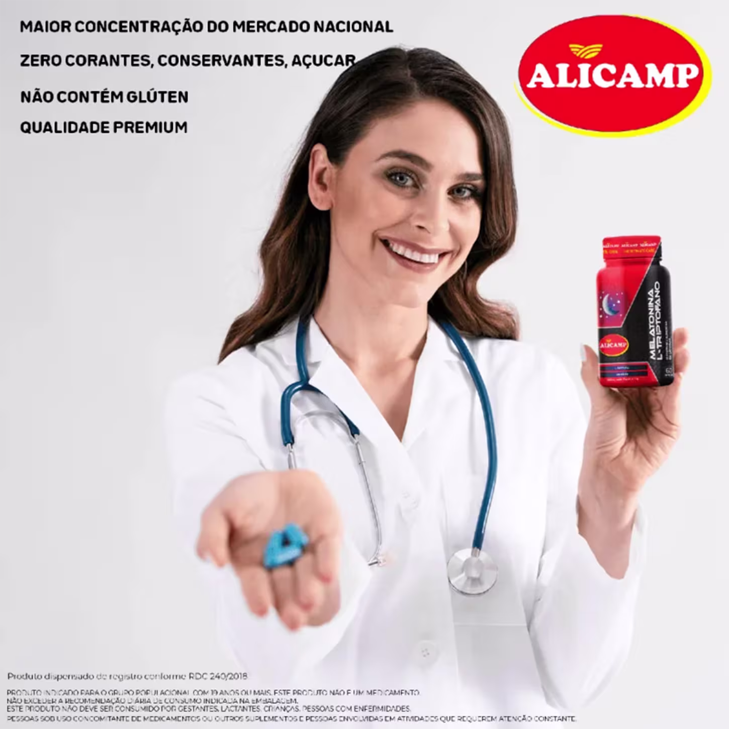 A imagem mostra uma mulher jovem branca de jaleco branco sorrindo e segurando o frasco de suplemento em uma mão e na outra comprimidos na cor azul.