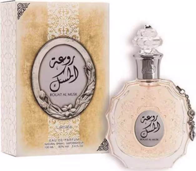 Frasco de perfume Lattafa Rouhat Al Musk com embalagem decorativa em tons claros, contendo texto árabe e detalhes florais. O produto é apresentado em um frasco de vidro com tampa decorativa.
