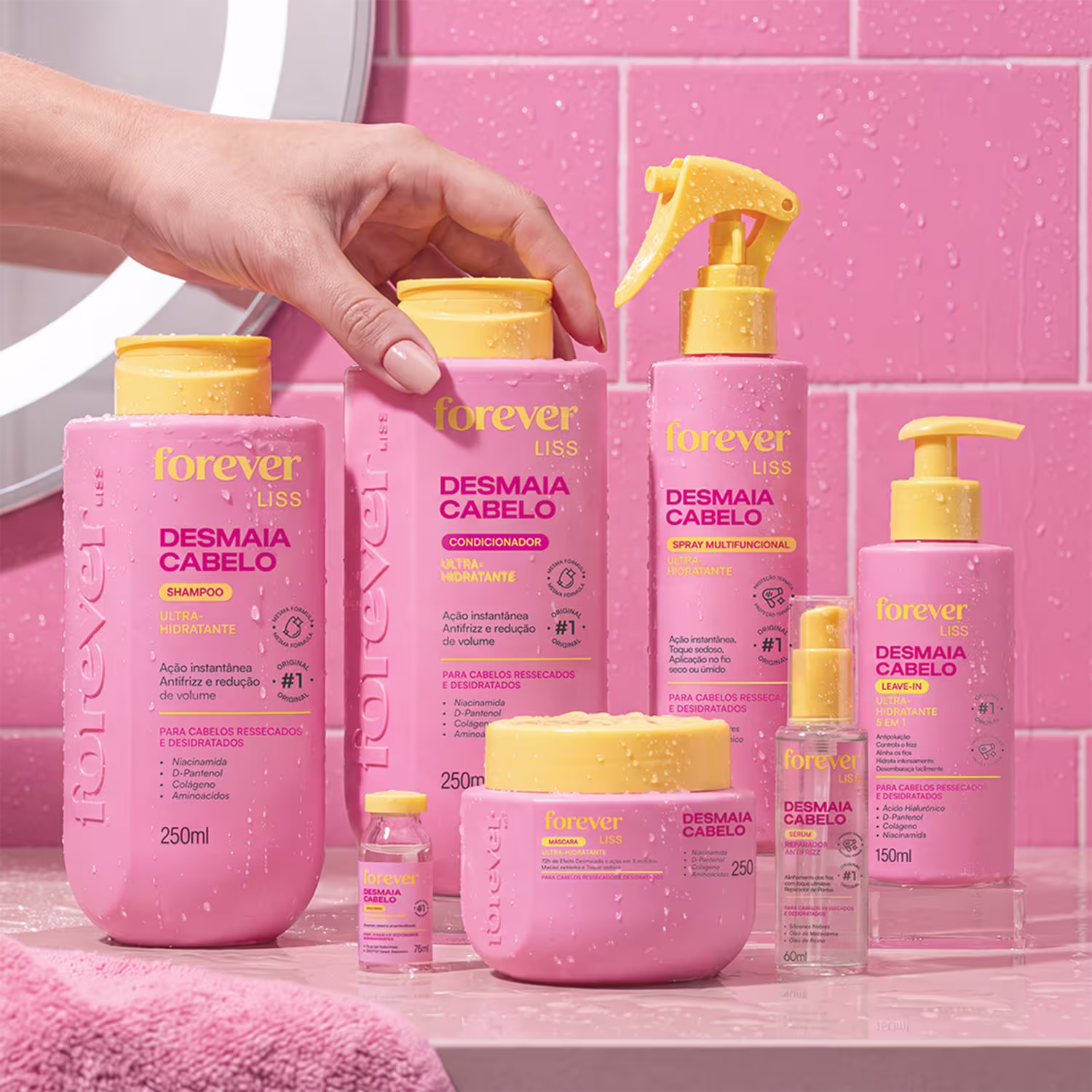 Produtos de beleza da linha Forever Liss, incluindo shampoo, condicionador, spray, sérum e leave-in, em embalagens rosa e amarelas com rótulos indicando os benefícios para cabelos ressecados e desidratados.