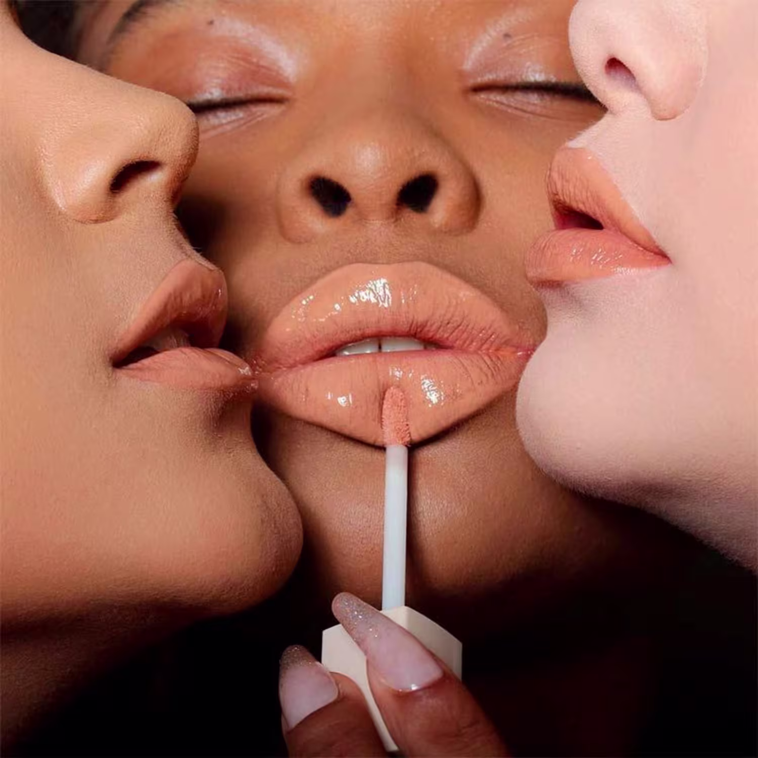 A imagem mostra três mulheres com lábios maquiados com o gloss brilhante, realçando o tom nos diferentes tons de pele.